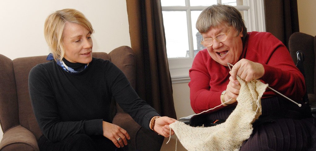 Support worker helping a client with knitting